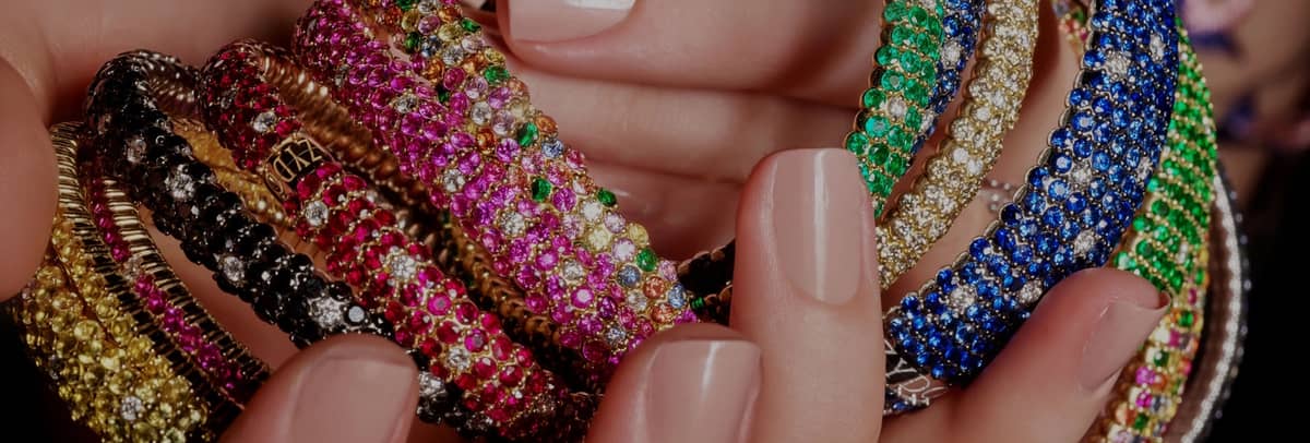 Stacks of multicolor pavé gemstone bangles held in hand